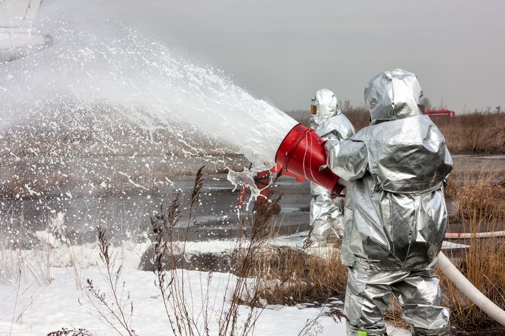 firefighters extinguishing fire with chemical foam