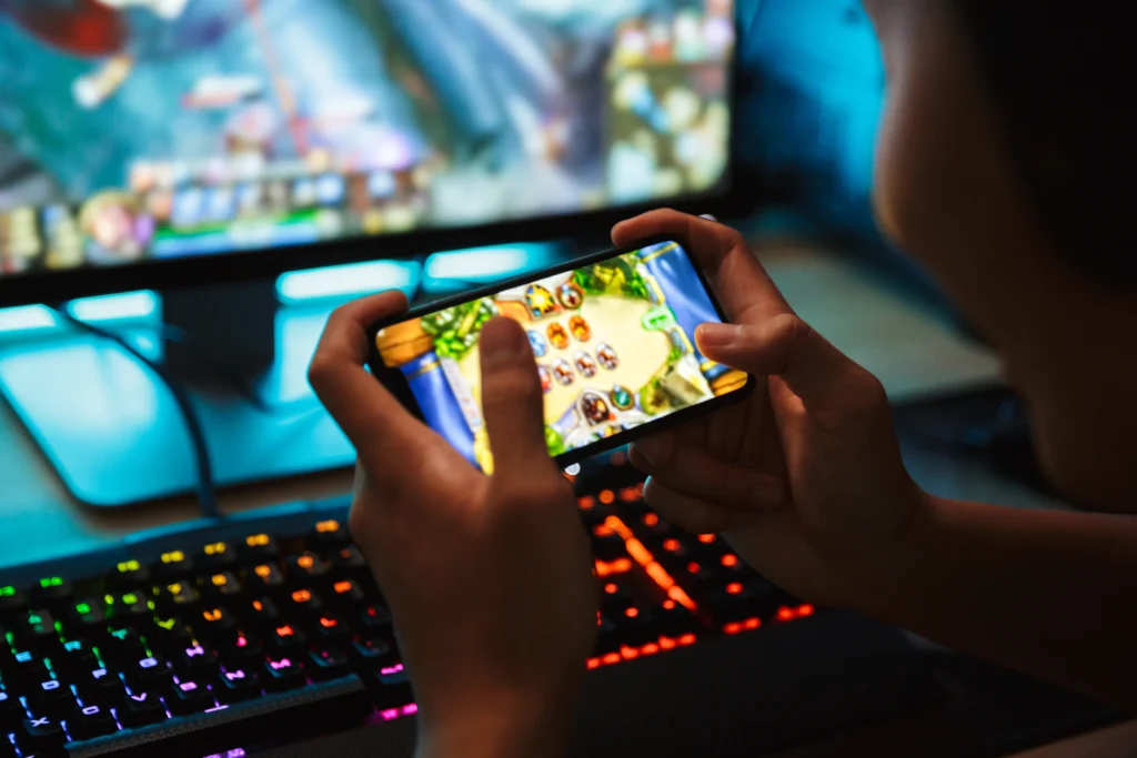 teen plays mobile phone game while playing computer game - Video Game Addiction Lawsuits - Lawsuit Legal News 