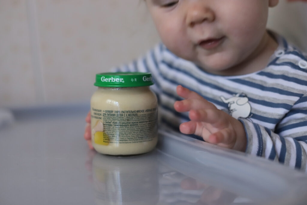 Baby interacting with jar of Gerber baby food who is a defendant in the toxic metals baby food lawsuit - LLN
