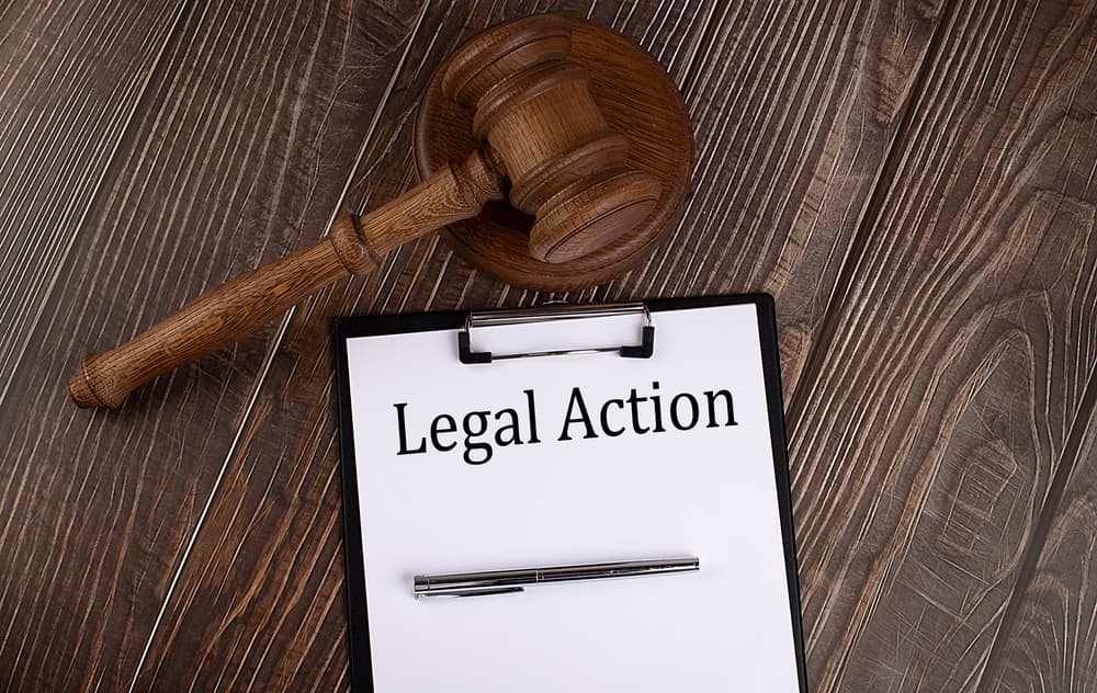 LEGAL ACTION text on the paper with gavel on the wooden background