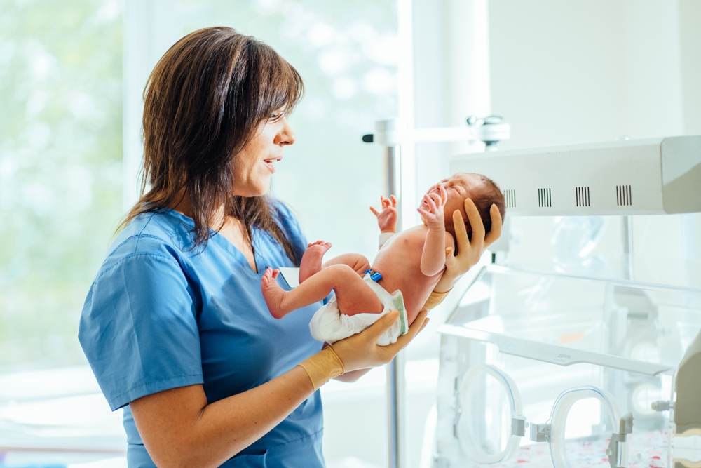 A healthcare professional holding a crying infant in a clinical setting, illustrating the medical monitoring required when infants show signs of phosphorus deficiency from elemental formulas.